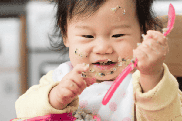 Baby holding a spoon and feeding herself