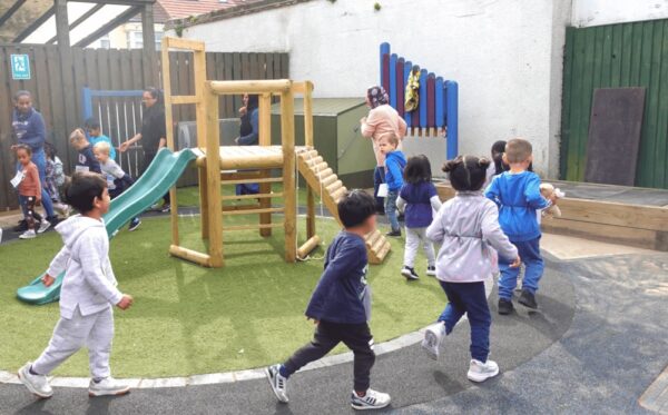 The daily mile in action, children running with nursery practitioners in the garden